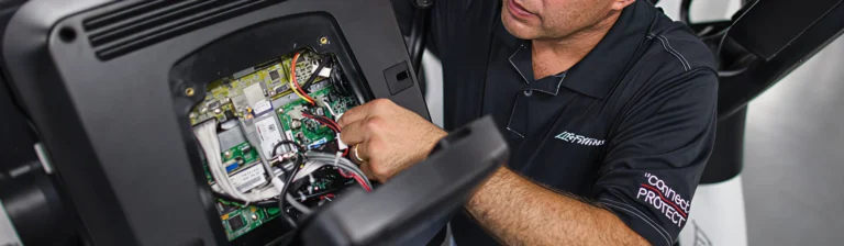 Technician servicing the opened console and control board of a cardio machine