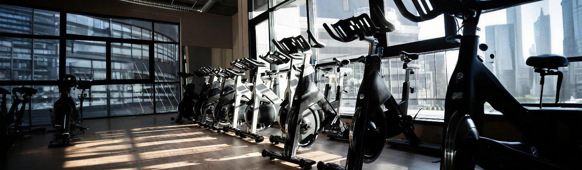 Row of indoor cycling bikes facing floor-to-ceiling windows