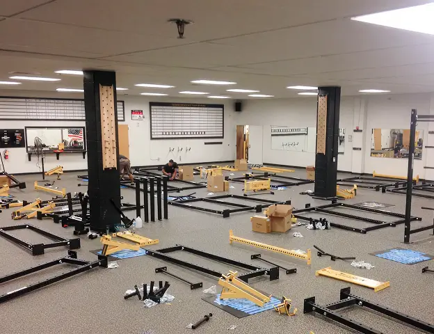 Fitness room mid-installation, with unassembled equipment, packaging and tools on the floor