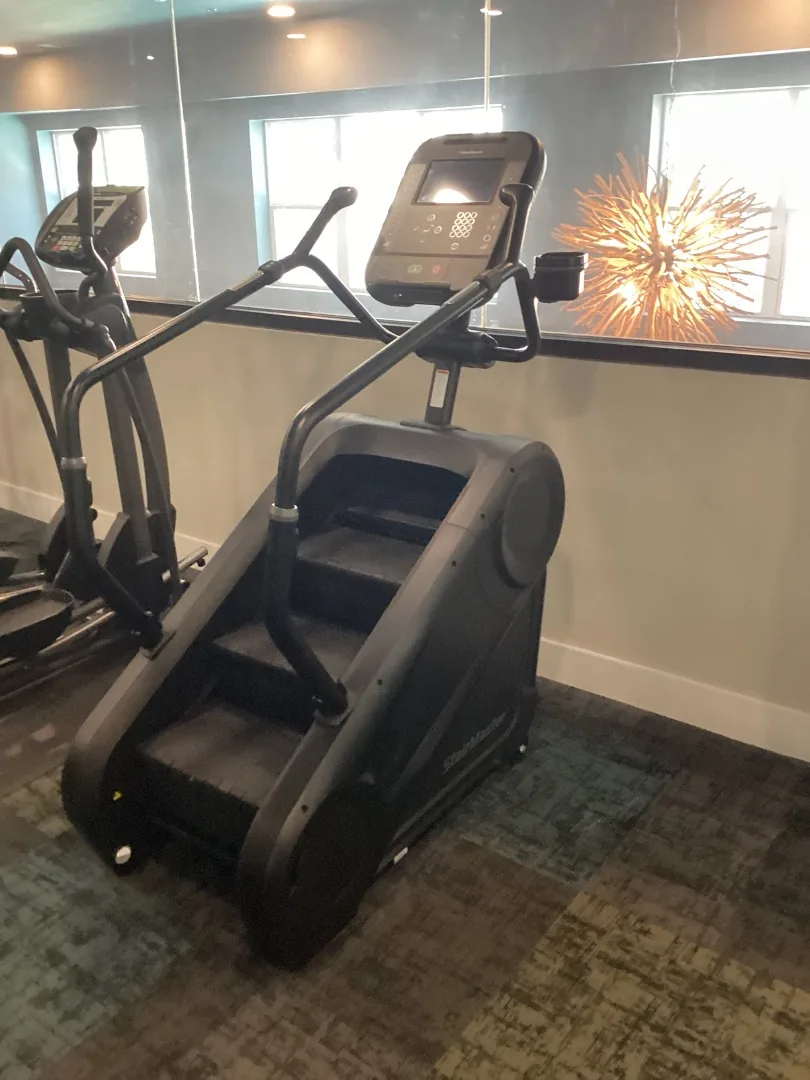StairMaster 4G StepMill stair climber in an apartment fitness room, an elliptical beside it