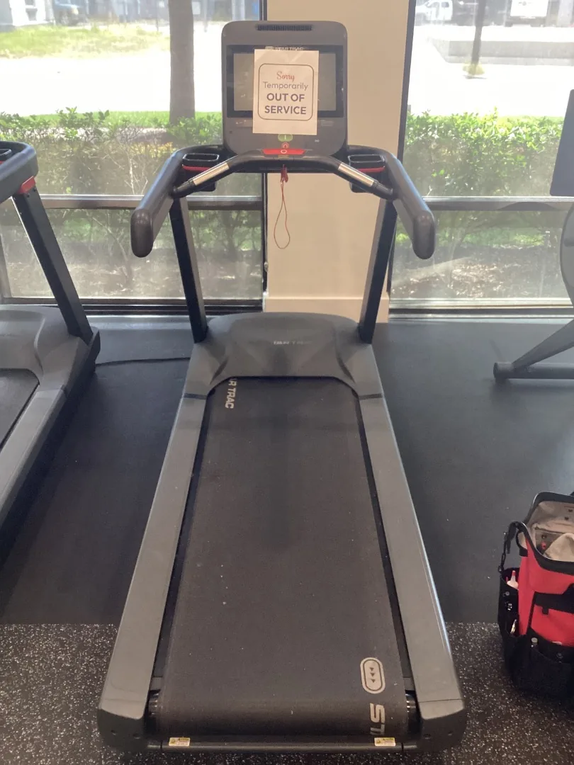 Star Trac treadmill with an out-of-service sign on its console, beside a window