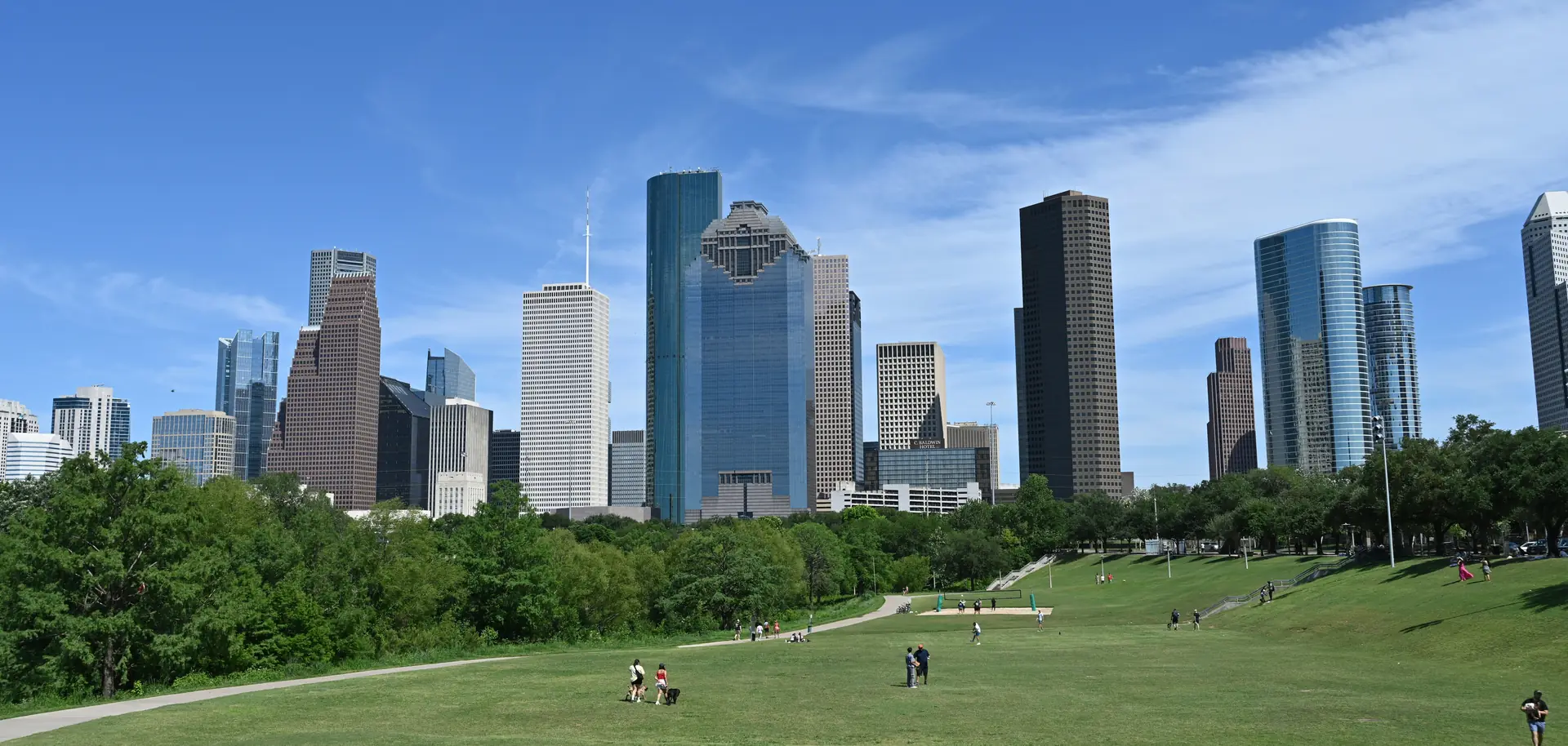 Downtown Houston skyline rising above a grassy park on a sunny day